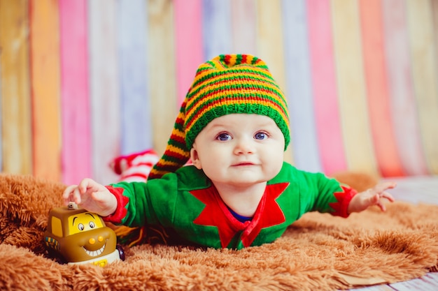 Photo gratuite un enfant habillé comme un elfe se trouve sur un tapis moelleux